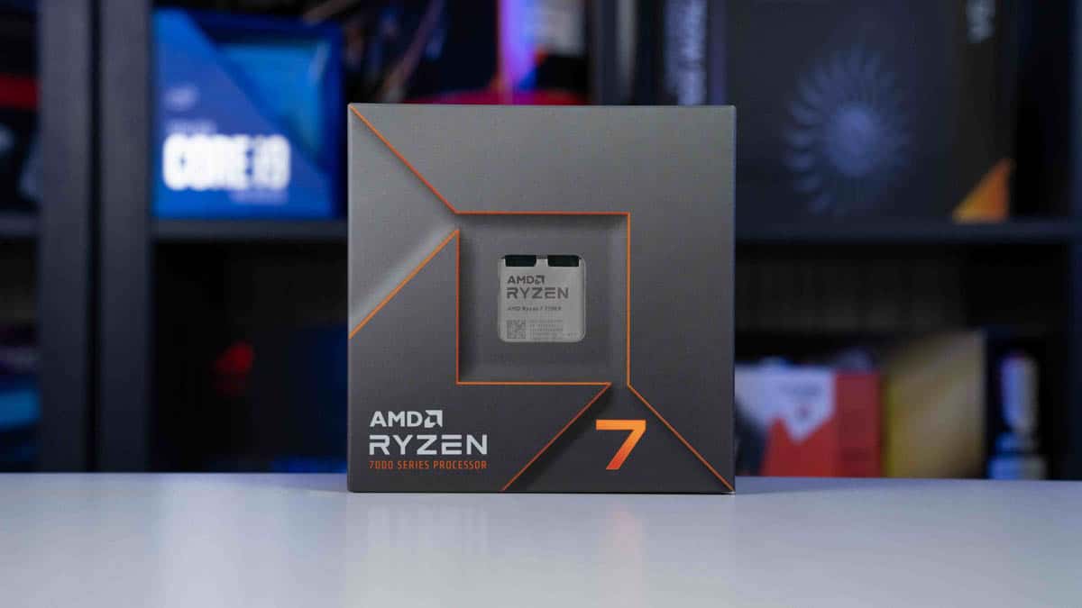 AMD Ryzen 7 7700X processor box on a table, with a blurred background featuring computer hardware.